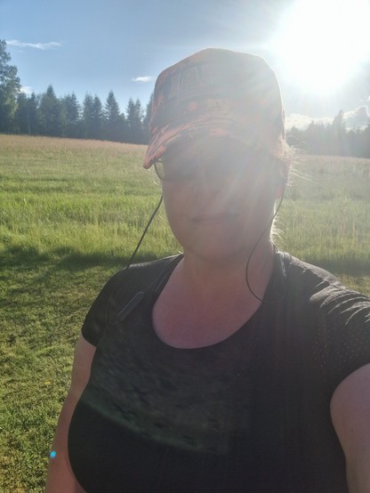 Selfie i motljus, det skymtar en äng och skog i bakgrunden. Jag är klädd för löpning. 