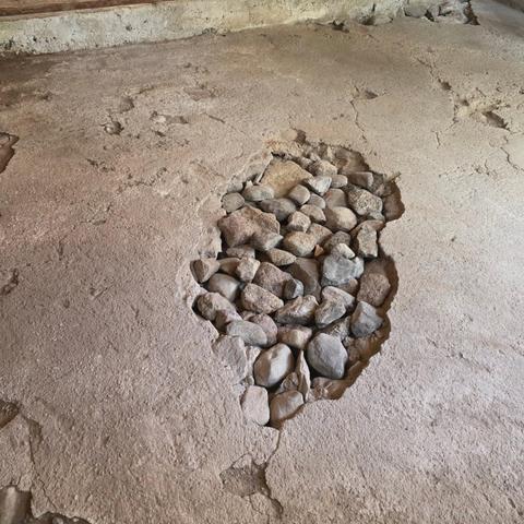 Ett hål i ett betonggolv med stenar, nu fria från smulig betong och skräp.