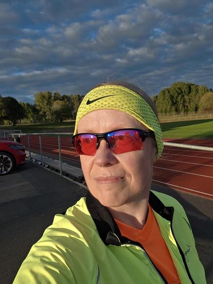 Selfie med en idrottsplatsen som bakgrund. Solen i ansiktet och mörka moln bakom.