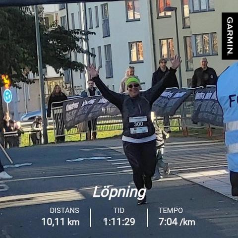 En målgångsbild från Jönköping 5/10K med en glad löpare som sträcker händerna i vädret. I bilden syns texten "Löpning, distans 10,11 km, Tid 1:11:29, Tempo 7:04 /km"