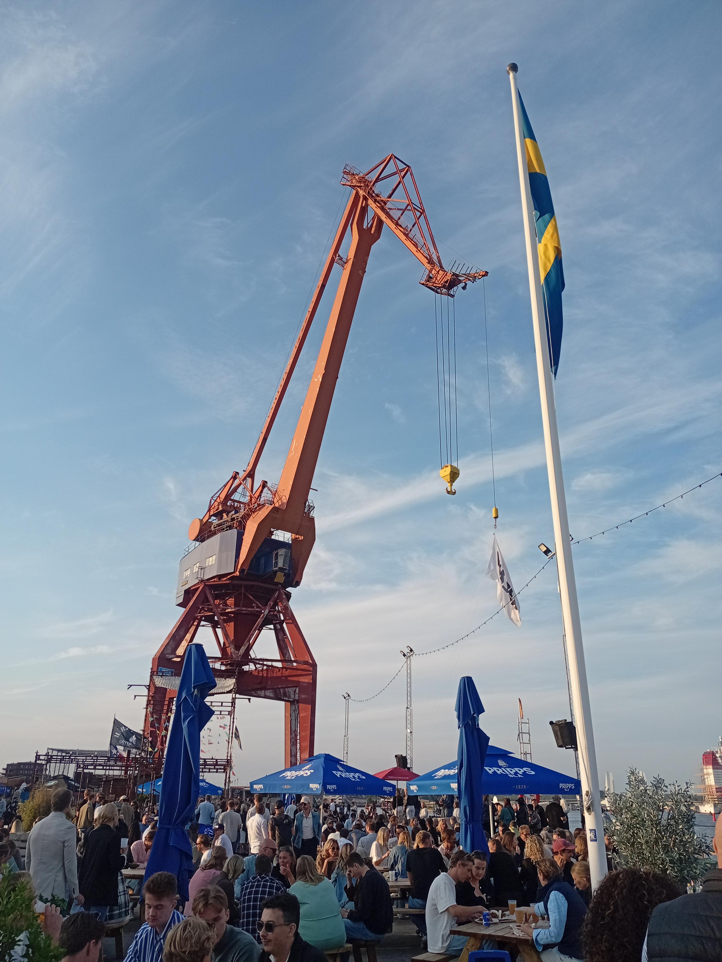 En gammal kran, en svensk flagga och en glad folkmassa.
