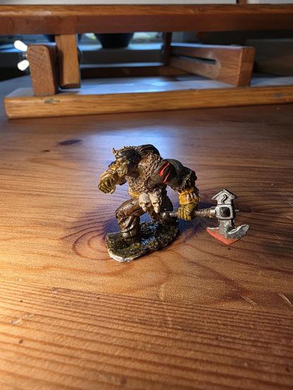 A tiny, handpainted orc wading through mud with blood on his axe.