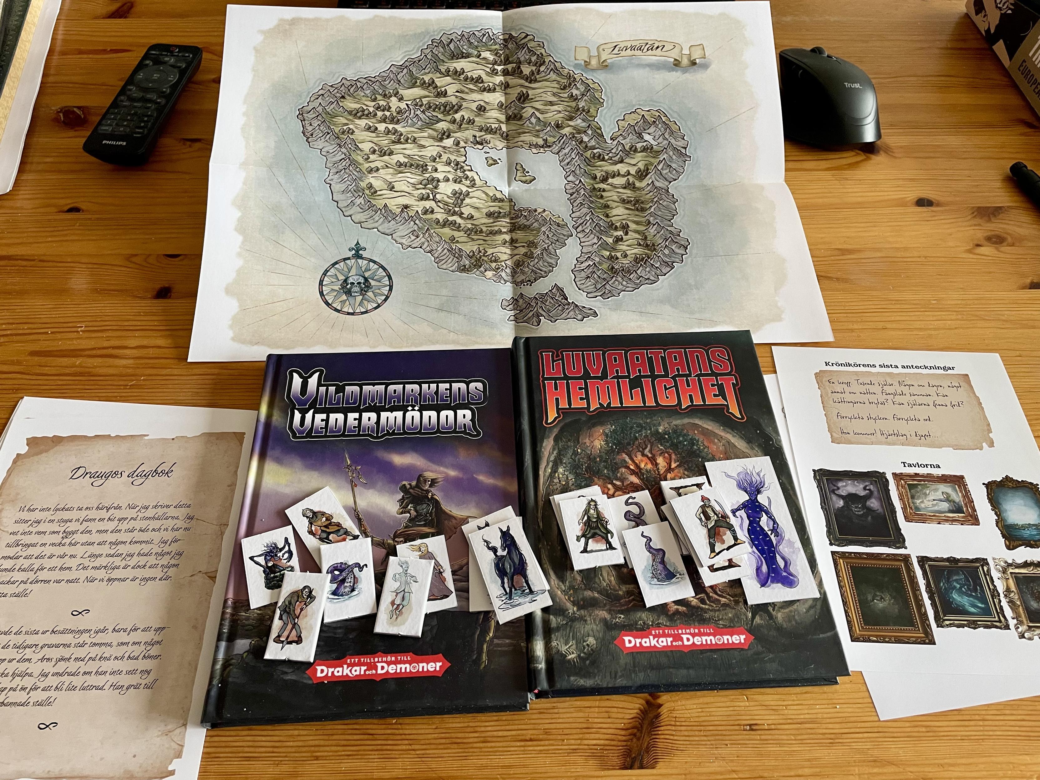 Två böcker till rollspelet Drakar och demoner, med tillbehör som karta och handouts till äventyret Luvataans hemlighet.