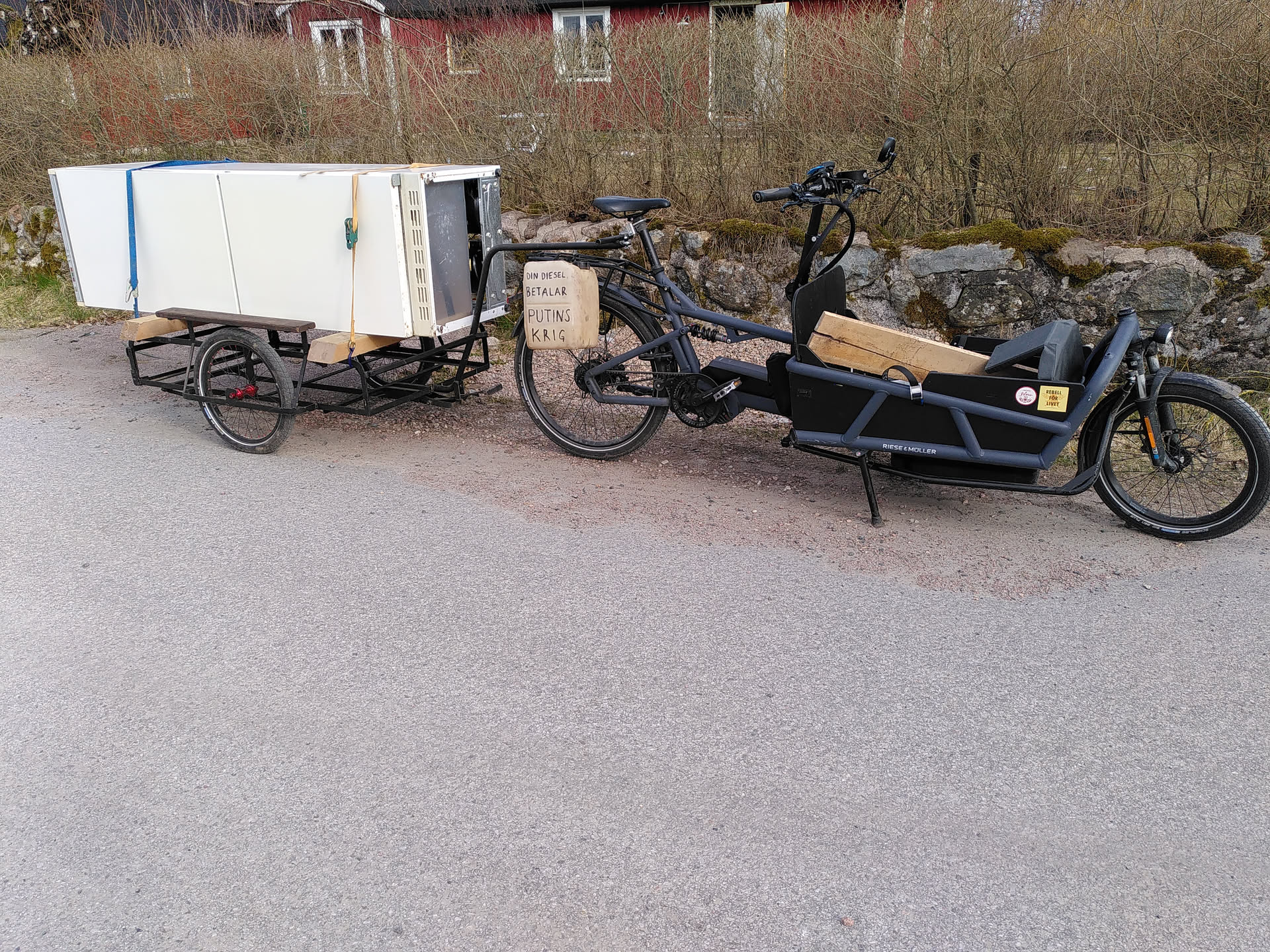 Long john style cargo bike with a trailer, the latter loaded with a fridge.