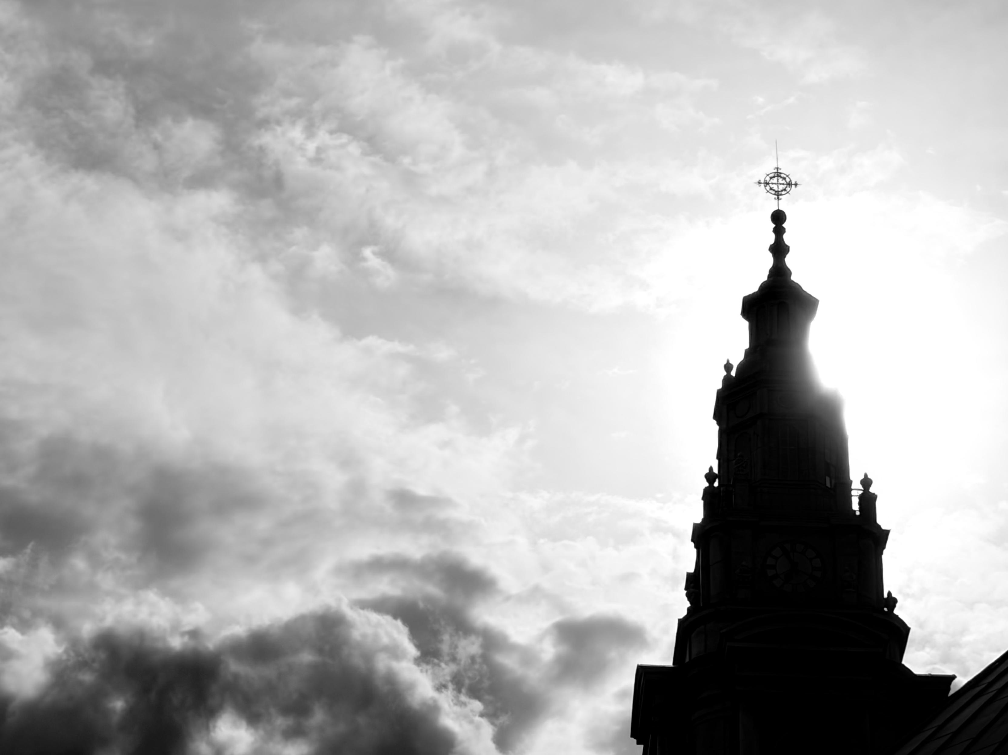Black and white photo of backlit church tower and clouds
