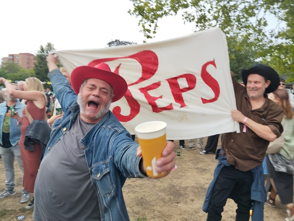 Två glada konsertbesökare med ett egenhändigt förfärdigat banner med texten Peps.